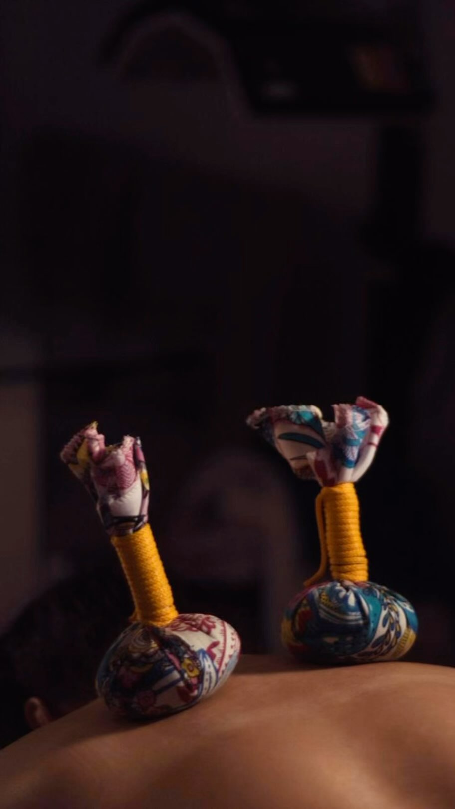 Dos pindas de tela estampada, rellenas de hierbas, apoyadas sobre una espalda